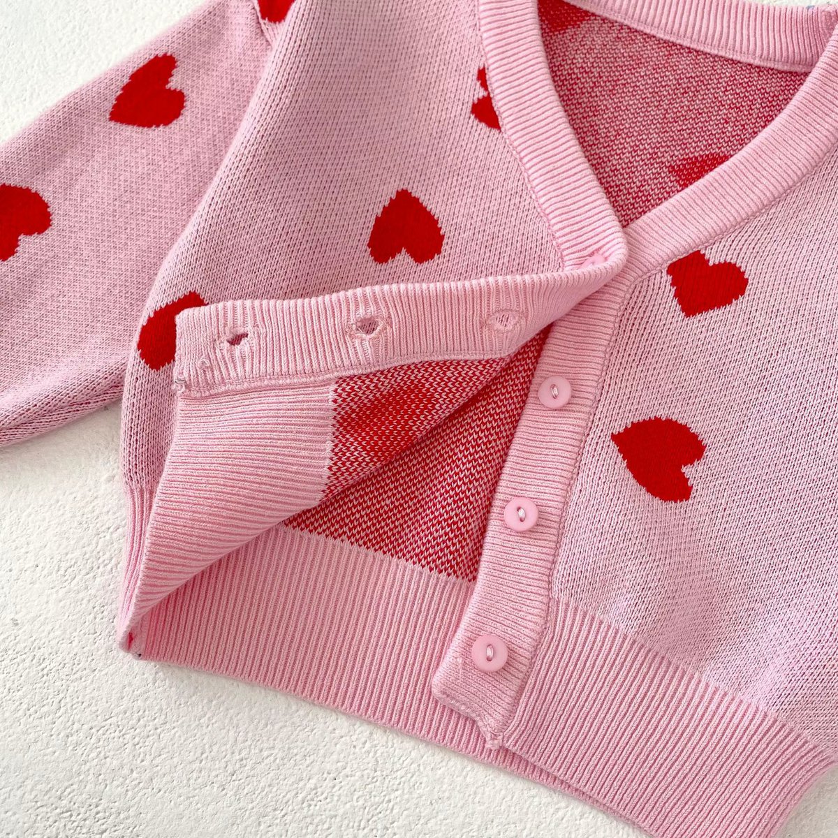 Detail van de rode hartjes op het roze babyvestje