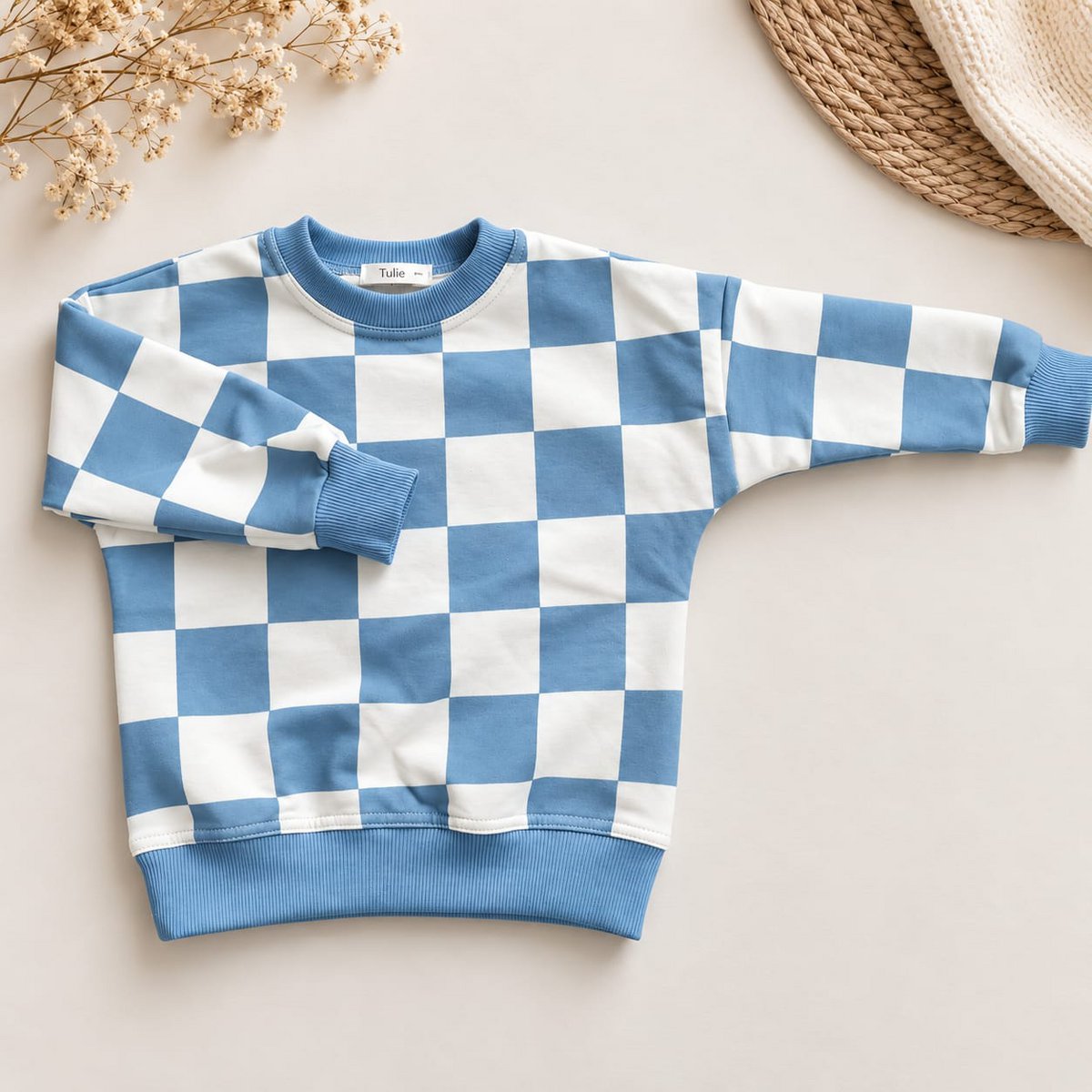 Kind draagt de blauwe dambord sweater