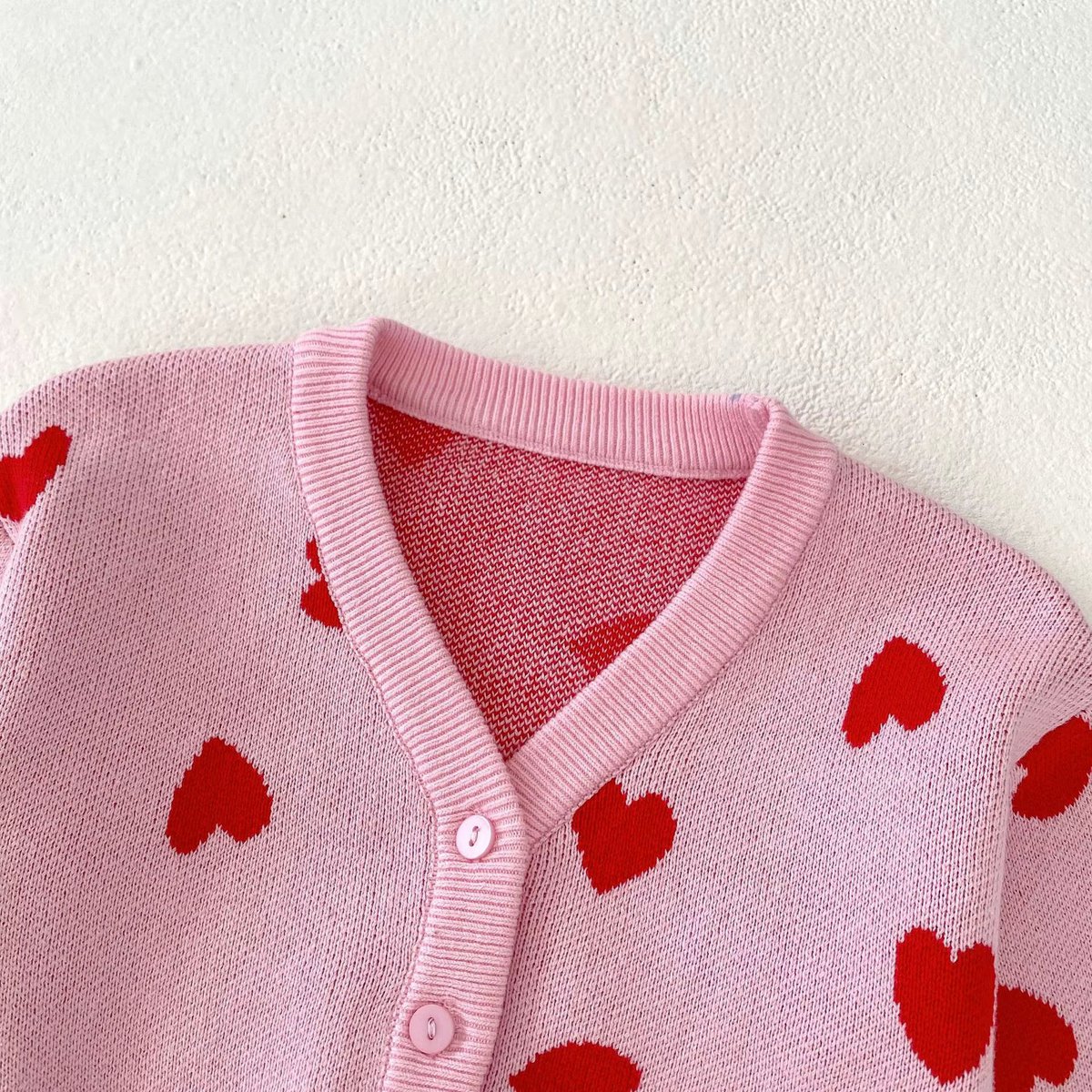 Roze hartjesvestje gedragen door een baby